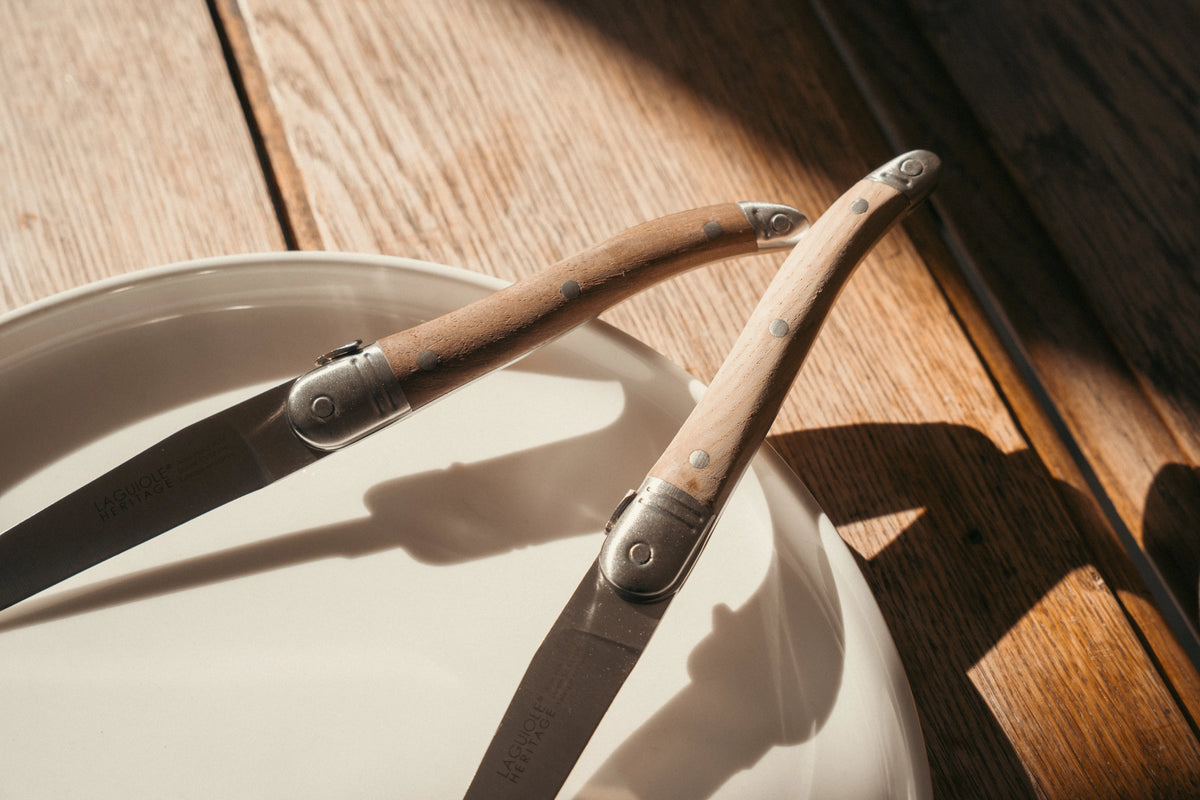 Couteaux de table Laguiole Héritage Médium manche bois sur une assiette